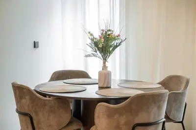 a table with chairs and a vase with flowers on it at Newly Furnished Vilnius Town Hall Apartments by Reside Baltic in Vilnius