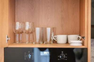 a shelf with wine glasses and cups on it at Newly Furnished Vilnius Town Hall Apartments by Reside Baltic in Vilnius