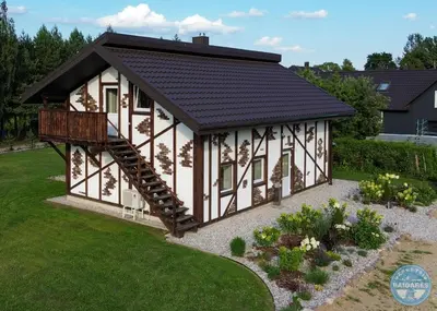 a house with a black roof and a balcony at Uždubysio baidarės Sodyba už Dubysos in Ariogala