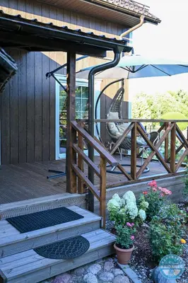 a wooden deck with a chair and an umbrella at Uždubysio baidarės Šimtametė Rezidencija in Ariogala