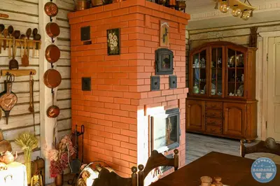 a brick fireplace in a room with a table at Uždubysio baidarės Šimtametė Rezidencija in Ariogala