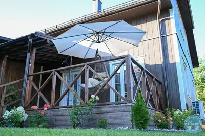 a house with an umbrella in front of it at Uždubysio baidarės Šimtametė Rezidencija in Ariogala
