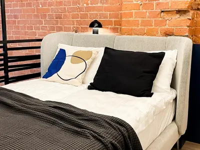 a couch with two pillows on it next to a brick wall at thePilots in Kaunas