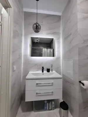 a white bathroom with a sink and a mirror at Refurbished central apartment in Vilnius