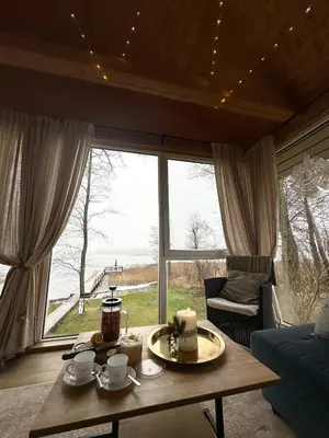 a living room with a table and a large window at Svedaso Lake House with Sauna in Svėdasai