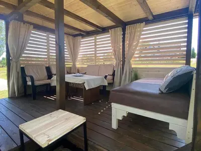 a room with a bed and a table on a deck at Svedaso Lake House with Sauna in Svėdasai
