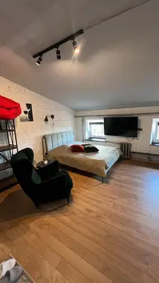 a bedroom with a bed and a chair and a television at Apartamentai Kauno centre in Kaunas