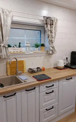 a kitchen with white cabinets and a sink and a window at Apgyvendinimas Rokiskyje namukas Skandis in Rokiškis