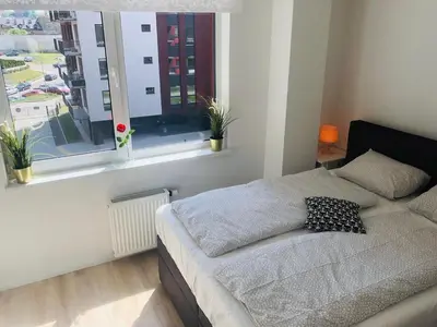 a bedroom with a bed and a window with plants at Brand New! 2Bdr 70m2 Old Town in Vilnius