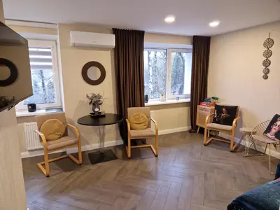 a living room with chairs and a table and windows at Petite City Centre Apartment self-check-in in Šiauliai