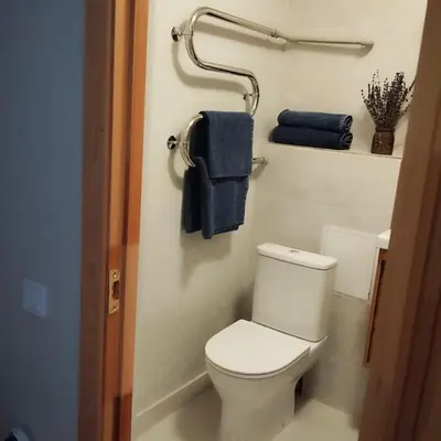 a bathroom with a white toilet and blue towels at Močiutės apartamentai in Anykščiai