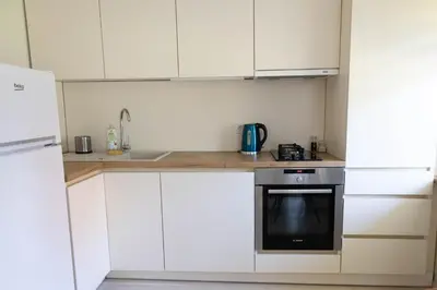 a kitchen with white cabinets and a sink and a stove at Močiutės apartamentai in Anykščiai