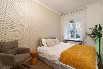 a bedroom with a bed and a chair and a window at Old Town Apartment on quiet private street in Vilnius
