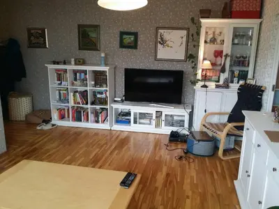 a living room with a television and a wooden floor at Lovely room in a centrally located flat in Vilnius