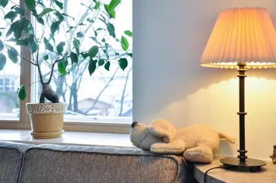 a teddy bear laying on a couch next to a lamp at Lovely room in a centrally located flat in Vilnius