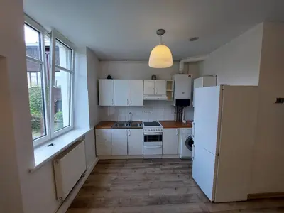 a kitchen with white cabinets and a white refrigerator at Treniotos Apartamentai in Vilnius