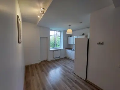 an empty kitchen with a refrigerator and a window at Treniotos Apartamentai in Vilnius