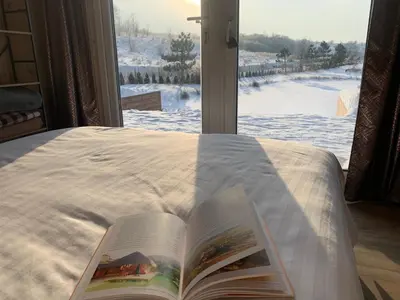 a book laying on a bed in front of a window at Aurora Resort in Stasiūnai