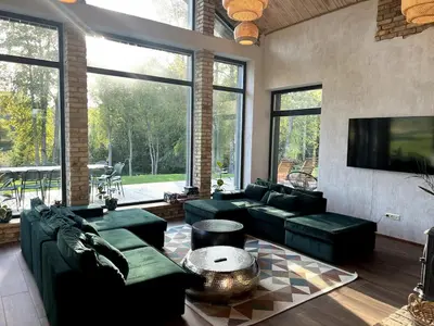 a living room with green couches and a flat screen tv at Kaimukas - lake house for 15 persons 5 bedrooms in Dvarčėnai