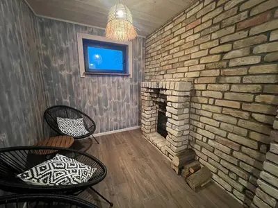 a brick wall with two chairs and a fireplace at Kaimukas - lake house for 15 persons 5 bedrooms in Dvarčėnai