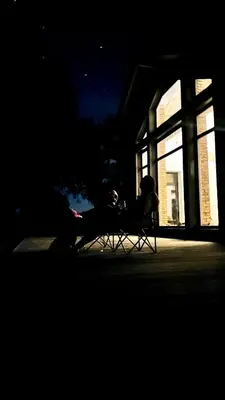 a person sitting in a chair in front of a building at Kaimukas - lake house for 15 persons 5 bedrooms in Dvarčėnai