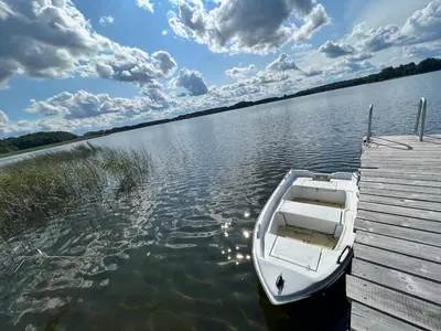 a white boat parked at a dock on a lake at Kaimukas - lake house for 15 persons 5 bedrooms in Dvarčėnai