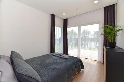 a bedroom with a bed and a large window at Lamėsto Krantas in Saldutiškis