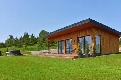 a small cabin with a deck and a lawn at Lamėsto Krantas in Saldutiškis