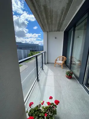 a balcony with red flowers and a chair on a building at Ralio apartamentai monkey in Vilnius