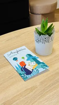 a book sitting on a table next to a plant at Light of Happiness in Anykščiai