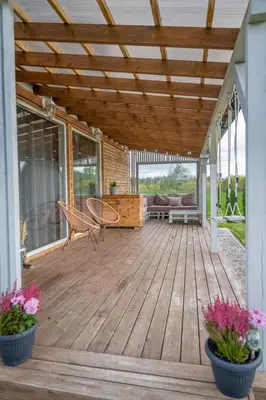 a wooden deck with two chairs and a couch at Poilsio oazė in Panevėžys