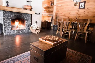 a living room with a fireplace and a table and chairs at Pakaso sodyba, šiaurinė pusė in Kirdeikiai