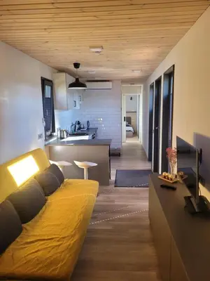 a living room with a yellow couch and a kitchen at Tiny House in Alytus