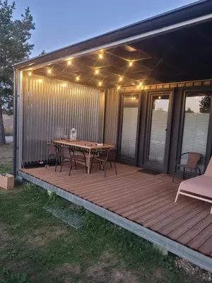 a deck with a picnic table and lights on it at Tiny House in Alytus