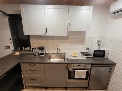 a kitchen with white cabinets and a sink at Tiny House in Alytus