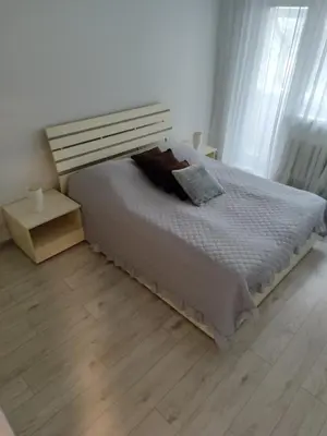 a bedroom with a bed and a wooden floor at Butas miesto centre in Šiauliai
