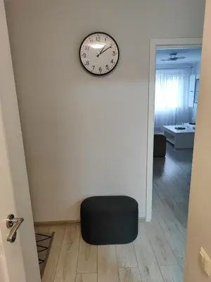 a black ottoman sitting in a room with a clock on the wall at Butas miesto centre in Šiauliai