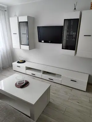 a white living room with a tv and a table at Butas miesto centre in Šiauliai