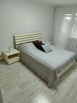 a white bedroom with a bed and a window at Butas miesto centre in Šiauliai