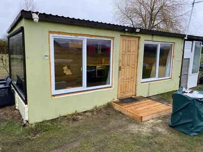 a green tiny house with a door and a porch at Karalgirio žvejų namelis in Karalgiris