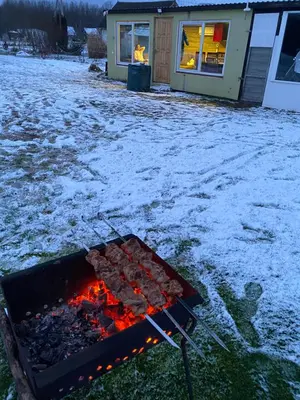 a grill with food on it in front of a house at Karalgirio žvejų namelis in Karalgiris