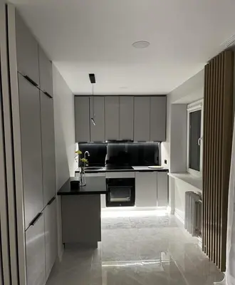 a kitchen with white cabinets and a black counter top at LUX Apartamentai in Marijampolė