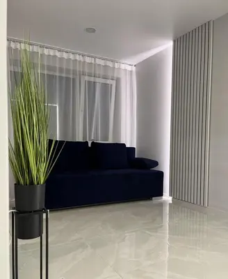 a living room with a blue couch and a plant at LUX Apartamentai in Marijampolė