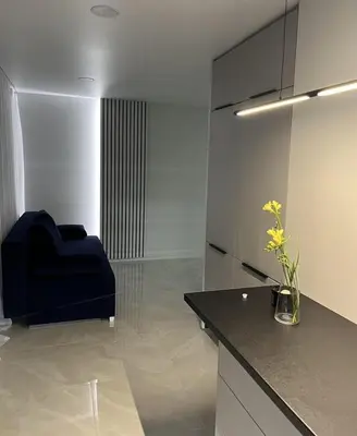 a kitchen with a blue chair and a black counter at LUX Apartamentai in Marijampolė