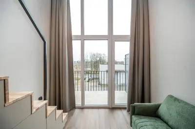 a living room with a green couch and a large window at Brand New Urban Lofts by Reside Baltic in Vilnius