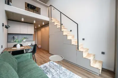 a living room with a green couch and a staircase at Brand New Urban Lofts by Reside Baltic in Vilnius