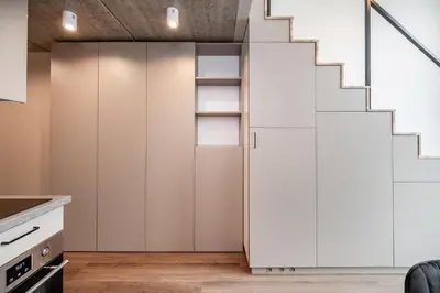a kitchen with white cabinets and a staircase at Brand New Urban Lofts by Reside Baltic in Vilnius
