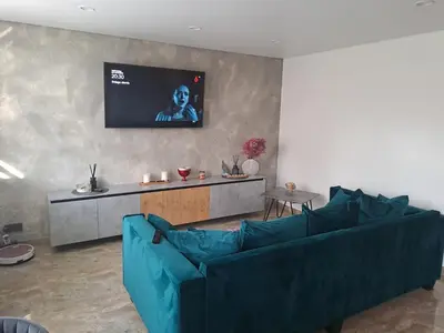 a living room with a blue couch and a flat screen tv at Kėdainiai Alinos Apartamentai in Kėdainiai