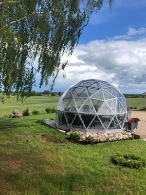 a domed greenhouse in a field with a tree at Poilsio oazė Stebuliuose in Stebuliai