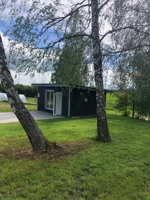 a black house with two trees in the grass at Poilsio oazė Stebuliuose in Stebuliai